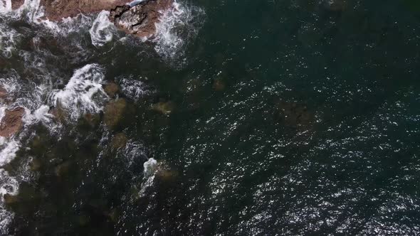 top view rising drone shot of raging waves of the pacific ocean at playa playitas breaking on the ro