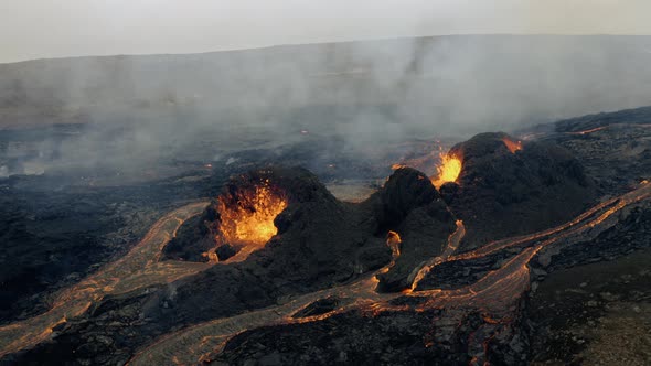 Slow motion aerial view of smoke over active, hot and continuous volcanic eruption with fresh flowin