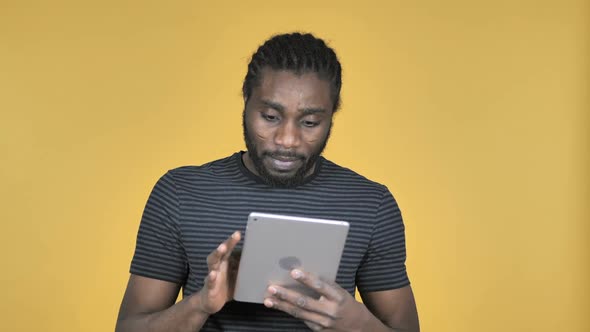 Casual African Man Excited for Success While Using Tablet Isolated on Yellow Background