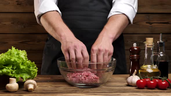 Closeup of Unrecognizable Chef's Male Hands Mixing Fresh Ground Beef in a Glass Bowl