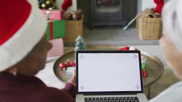 Two happy diverse senior woman on video call on laptop with copy space at christmas time