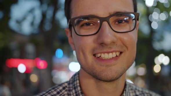 Close-up Portrait of Happy Young Brunet in Glasses Standing Outdoors in Evening