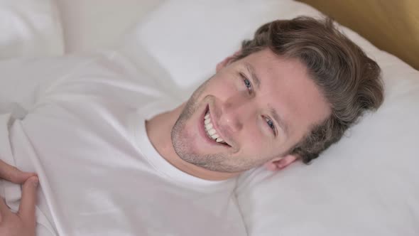 Portrait of Young Man Smiling at Camera From Bed