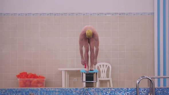 A Man in Yellow Cap Jumps Down in the Swimming Pool From the Stand