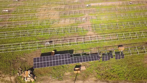 Aerial view of solar power plant under construction on green field. Assembling of electric