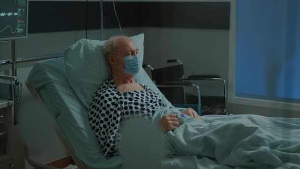 Sick Patient Sitting in Hospital Ward Bed with Face Mask