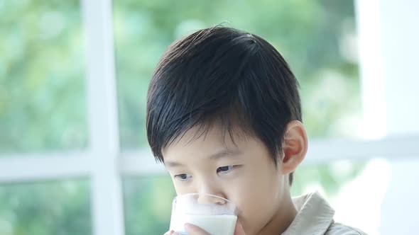 Cute Asian child drinking milk from a glass