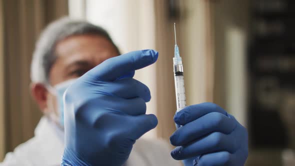 Senior mixed race male doctor preparing vaccination syringe