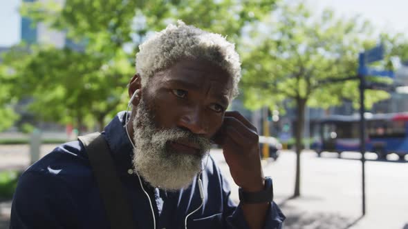 Close up of african american senior man in face mask wearing earphones on the road