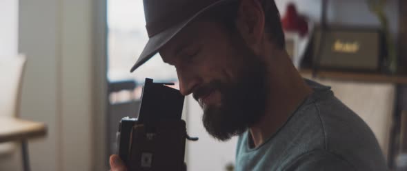 Bearded man smiling and looking through a visor of a vintage camera