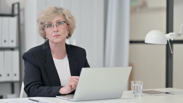 Old Businesswoman with Laptop Looking at Camera