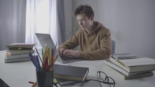 Exhausted Caucasian Student Getting Asleep at Laptop While Studying. Portrait of Tired Brunette Boy