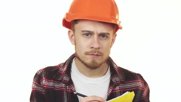 Young Professional Male Architect in a Hardhat Making Notes