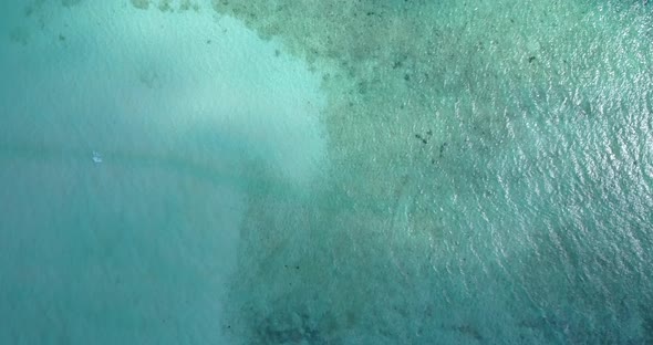 Wide angle overhead tourism shot of a sandy white paradise beach and aqua blue water background in c