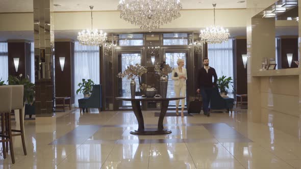 Extreme Wide Shot of Caucasian Man and Woman with Travel Bag Entering Luxurious Hotel Vestibule and