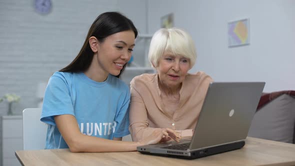 Nursing Home Volunteer Teaching Aged Lady to Use Laptop