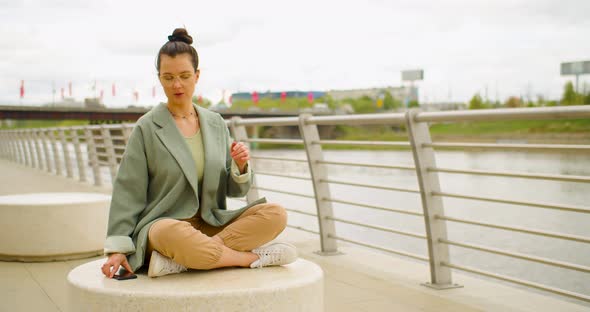 A Woman Takes Off Her Eyeglasses Puts Down Her Phone and Begins to Meditate