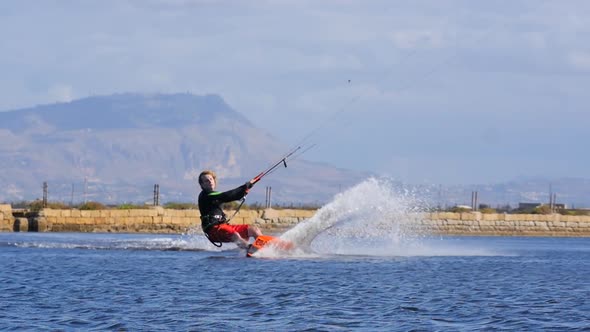 A man kiteboarding and doing a jumping trick on a kite board.