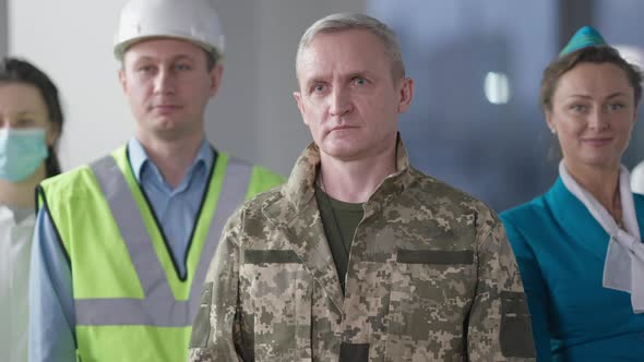 Handsome Senior Confident Soldier Crossing Hands with Blurred Stewardess Builder and Doctor in