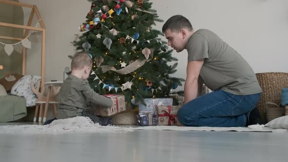 Cute Child Boy and Dad Put Gifts Under Xmas Tree