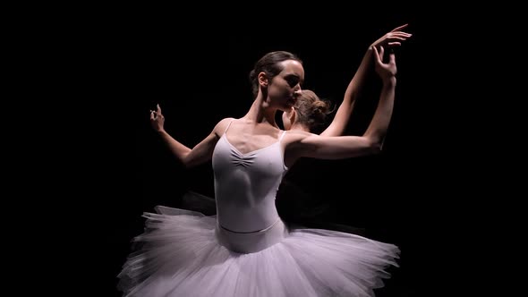 Camera Rotates Around Two Flexible Ballerinas in Black and White Tutus Move Their Hands Dramatically