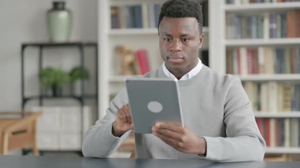 African Man Using Tablet While Sitting in Library