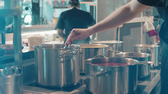 Restaurant Cook is Stirring Food in Pots