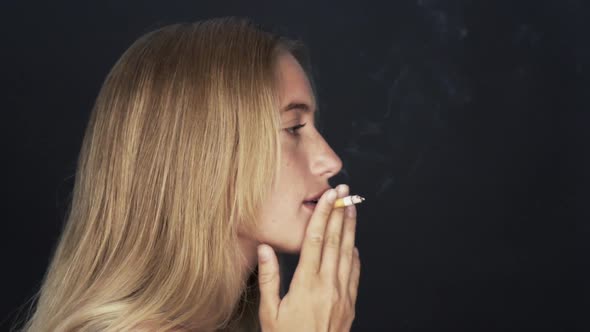 Young woman smoking cigarette, turning and smiling over shoulder