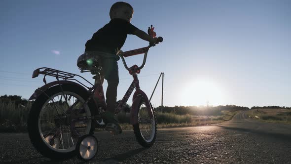 Little Boy Learning To Ride on Bicycle on Sunset Time.