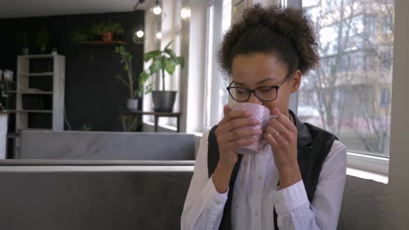 Coffee Break of Happy Black Teen Girl Into Glasses with Cup Hot Drink Close-up at Cafe in Leisure