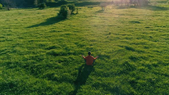 Low Altitude Radial Flight Over Sport Yoga Man at Perfect Green Grass. Sunset in Mountain.