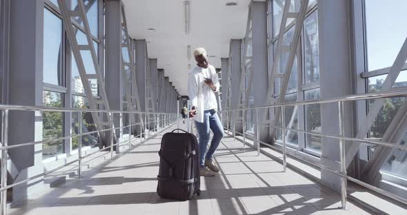 African Guy Stylish Trendy Mixed Race Model Man Carrying Suitcase Luggage, Dancing Alone in Airport