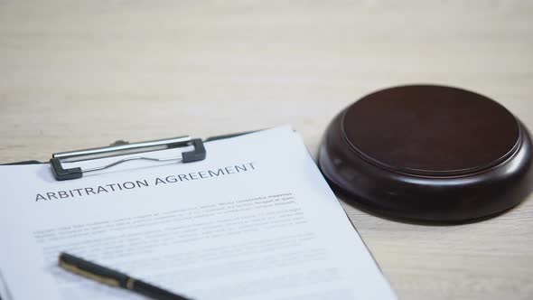 Arbitration Agreement Document on Table, Gavel Striking on Sound Block, Dispute