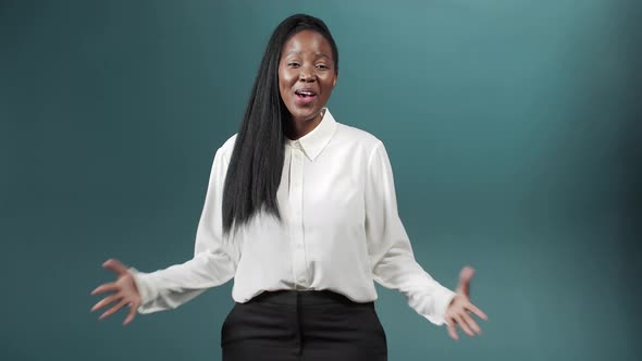 An Attractive Cheerful African Girl with Long Hair is Talking to the Camera Smiling and Gesturing