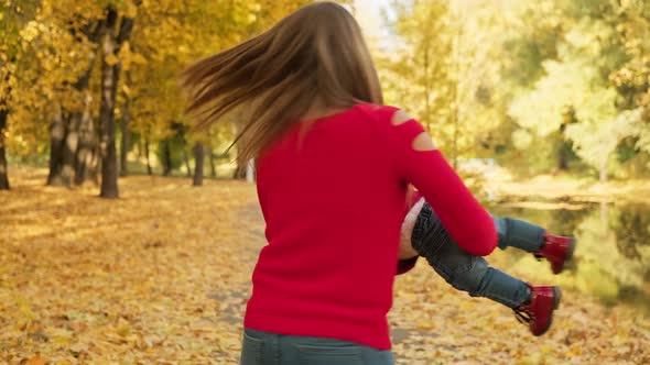 Mom Holding Daughter in Autumn Park