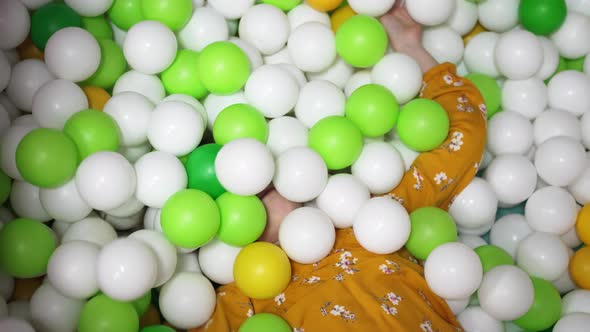 a Little Girl Plays in a Dry Pool with White Yellow and Green Plastic Balls