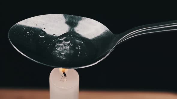 Preparing a Dose of Heroin in a Spoon Over a Candle Flame