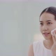 Happy Asian girl looking in to mirror, holding cotton pad, applying facial wipe on her face. - VideoHive Item for Sale