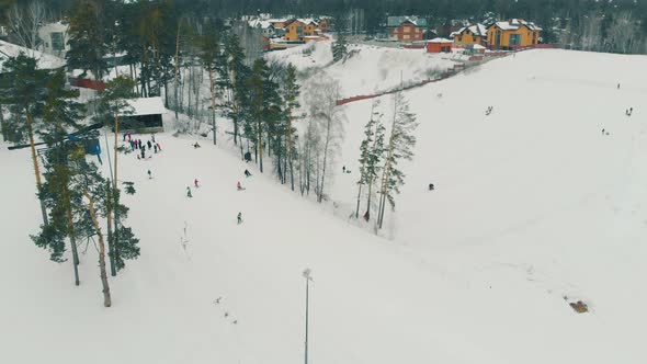 People in Multicolored Ski Suits Move Down Big Snowy Slope