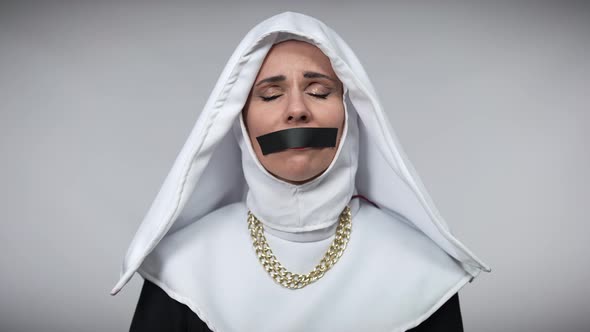 Desperate Hopeless Woman in Nun Costume with Mouth Closed with Black Tape Holding Hands Together