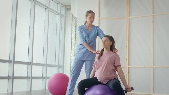 A Health Worker at a Medical Center Helps a Pregnant Woman to Do Exercises