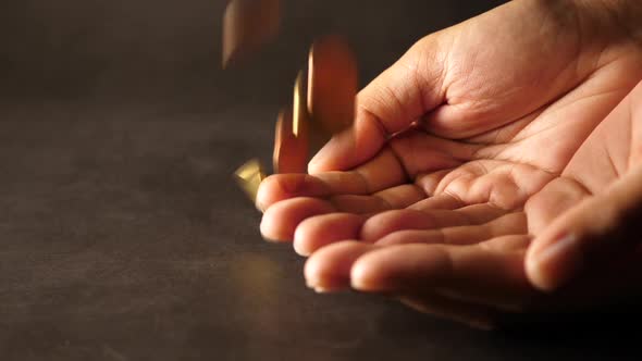 Hand holding a big heap of coins and throwing them on table