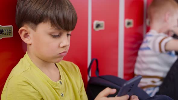 Close up video of schoolboy using smartphone in school corridor. Shot with RED helium camera in 8K.