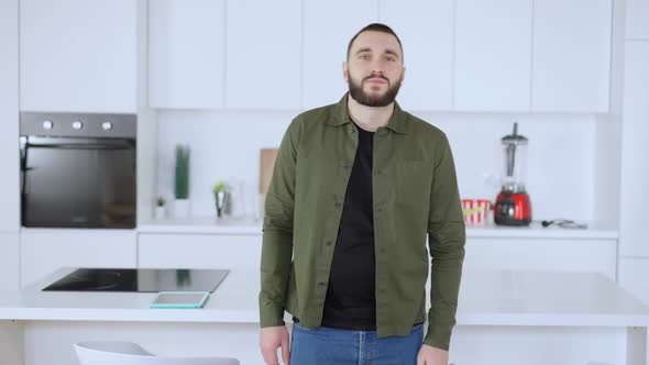 Middle Shot of Confident Caucasian Man Posing in Kitchen Crossing Hands and Looking at Camera