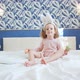 A Cute Little Girl with Long Hair Sits in Center of a Large Bed and Plays with Decorative Rabbit - VideoHive Item for Sale