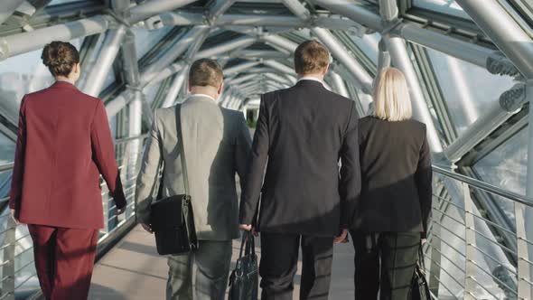 Business People Walking Along Glass Bridge