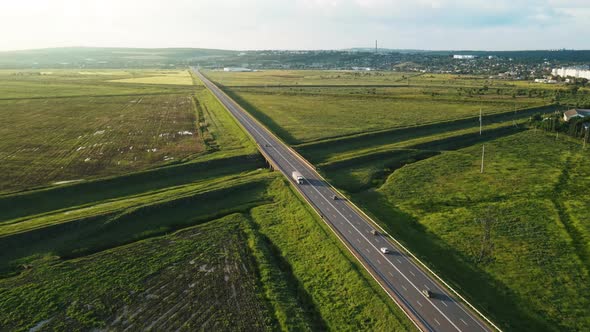 Aerial drone view of a highway with cars, village, a lot of greenery, fields in Moldova