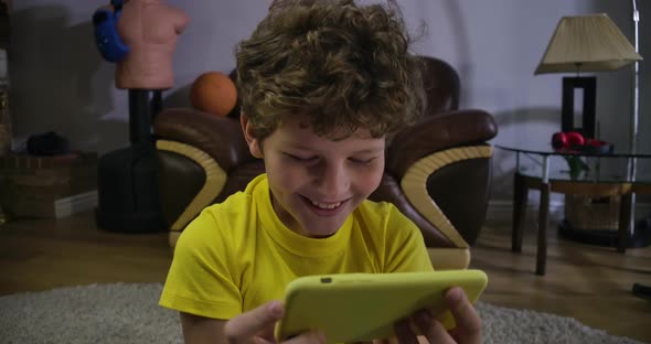 Close-up Face of Caucasian Curly-haired Boy Watching Comedy Show at Smartphone Screen. Joyuful Kid