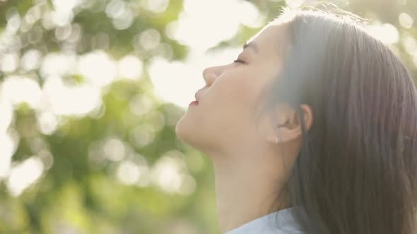 Close-up portrait of young Asian woman relaxed enjoying peaceful sunset.