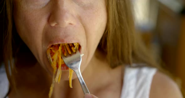 Close-up Portrait of a Dark-haired Middle-aged Woman Sitting at a Table, She Eats, in Front of Her